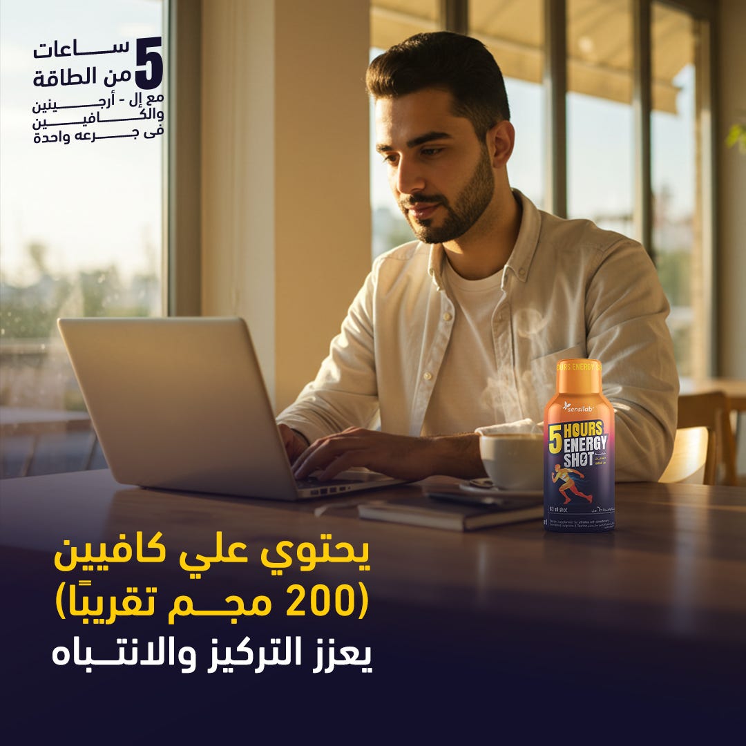 Man working on a laptop with a bottle of '5 Hours Energy Shot' in front of him.